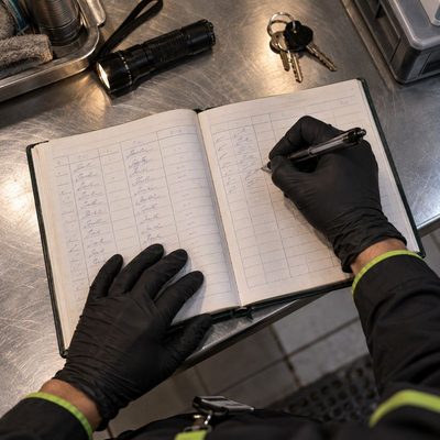 Illustrative image: a technician writing a dated entry in a bound service logbook
